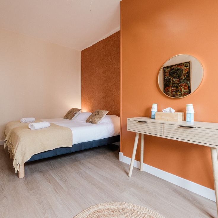 Chambre confortable avec lit double, décoration moderne, et murs aux teintes chaudes.